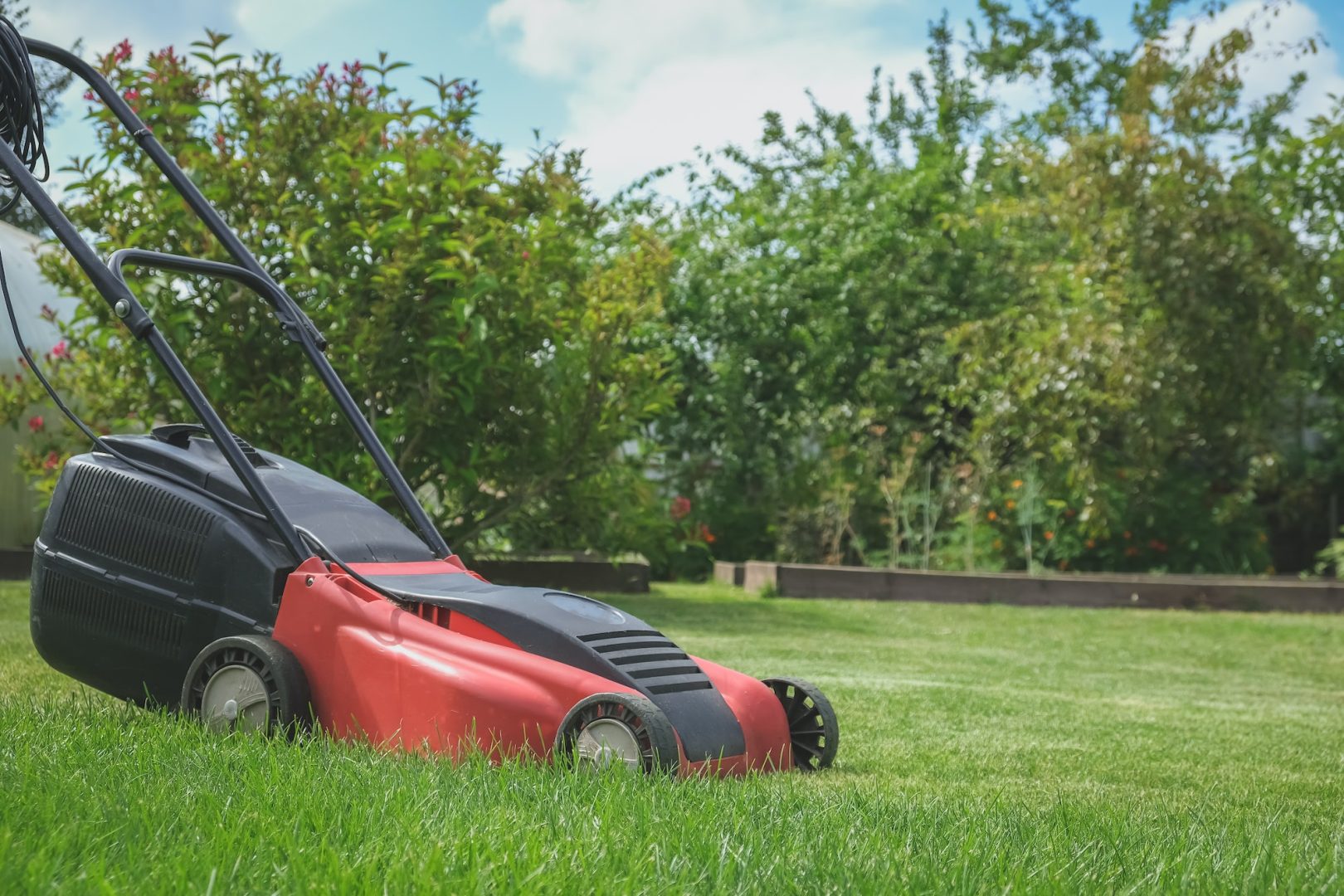 Lawn mower on green grass in a modern garden. Lawn Mowing Machine Gardening, Agriculture, Organic